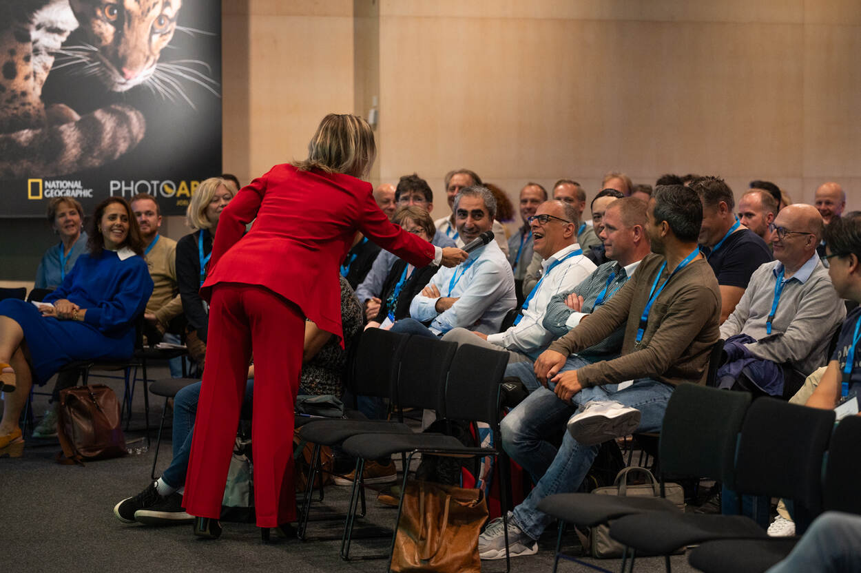 Foto van de dagvoorzitter Desiree Hoving die een deelnemer wat laat zeggen in de microfoon